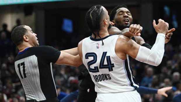 Cleveland Cavaliers guard Donovan Mitchell (45) throws a punch at Memphis Grizzlies forward Dillon Brooks (24) as referee Jonathan Sterling (17) tries to break them apart during the second half at Rocket Mortgage FieldHouse. Both players were ejected.